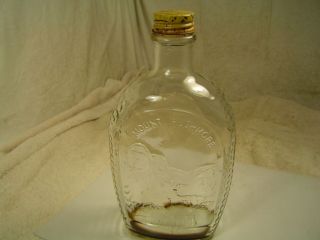 Empty clear glass Log Cabin Syrup bi centennial bottle.